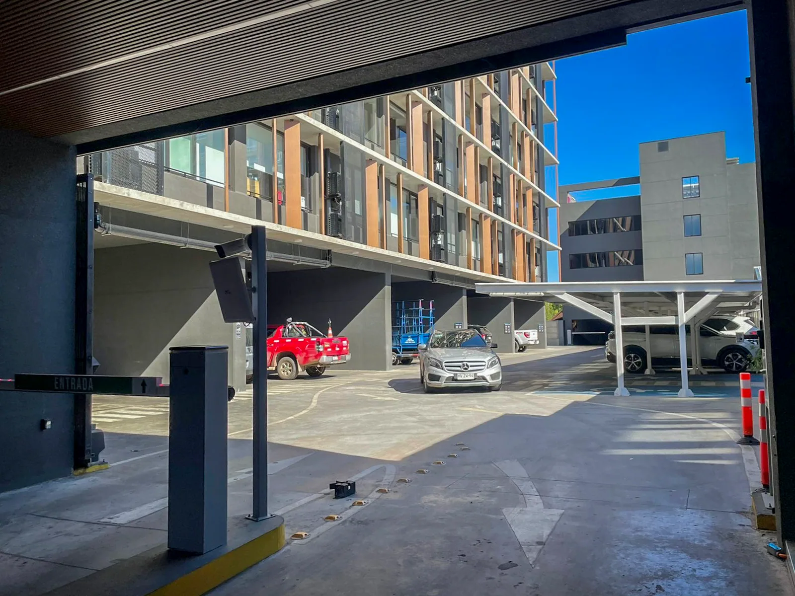 Barrera de acceso y zona de estacionamiento techada junto a la torre